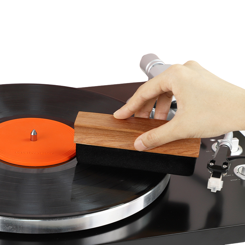 A hand holding velvet record cleaning brush on a record to demonstrate how to clean the record