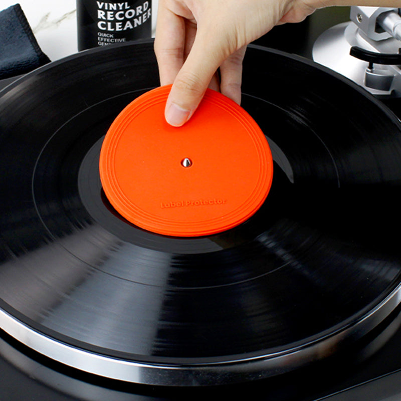 A hand putting the vinyl survival record label protector on a LP